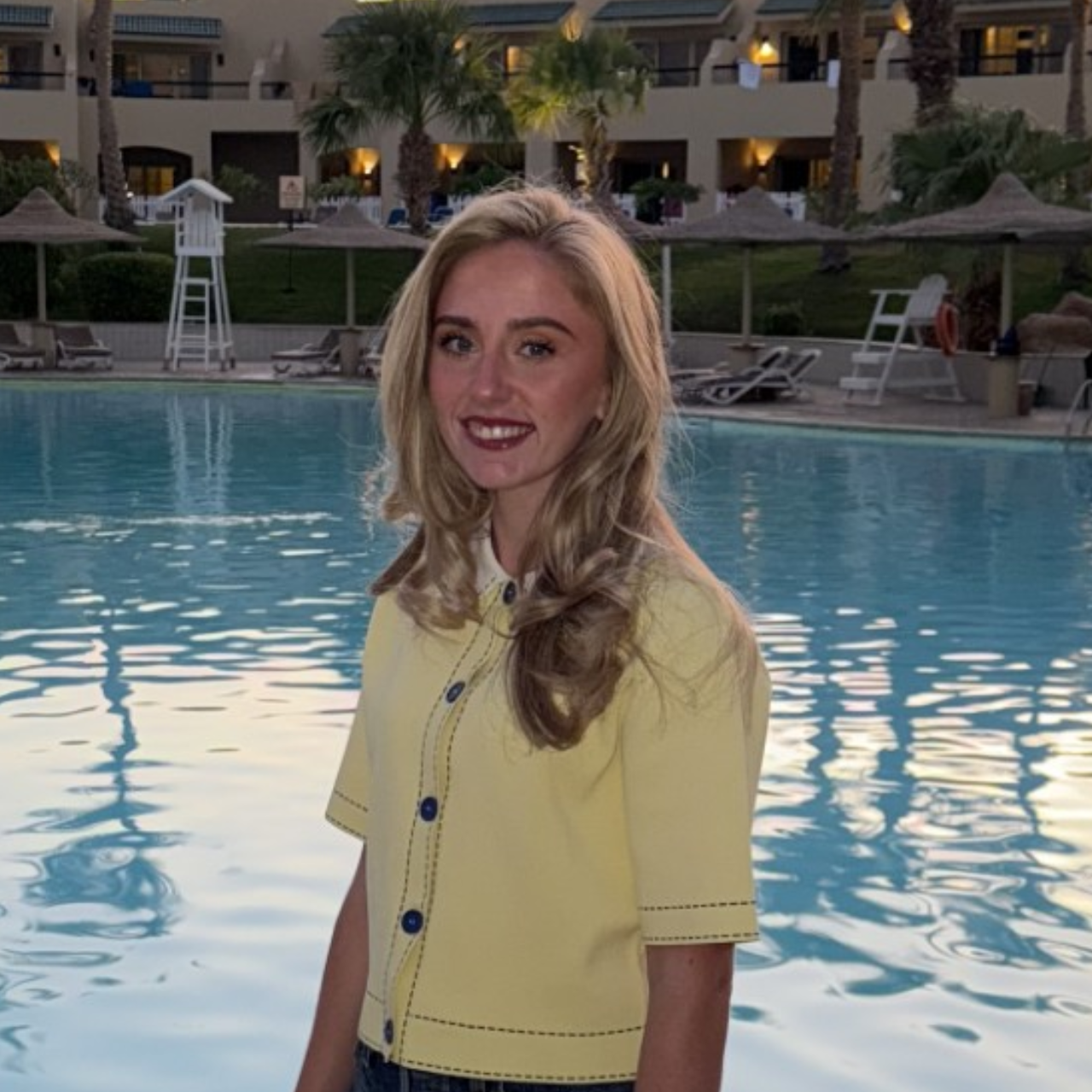 a student standing in front of a pool, smiling