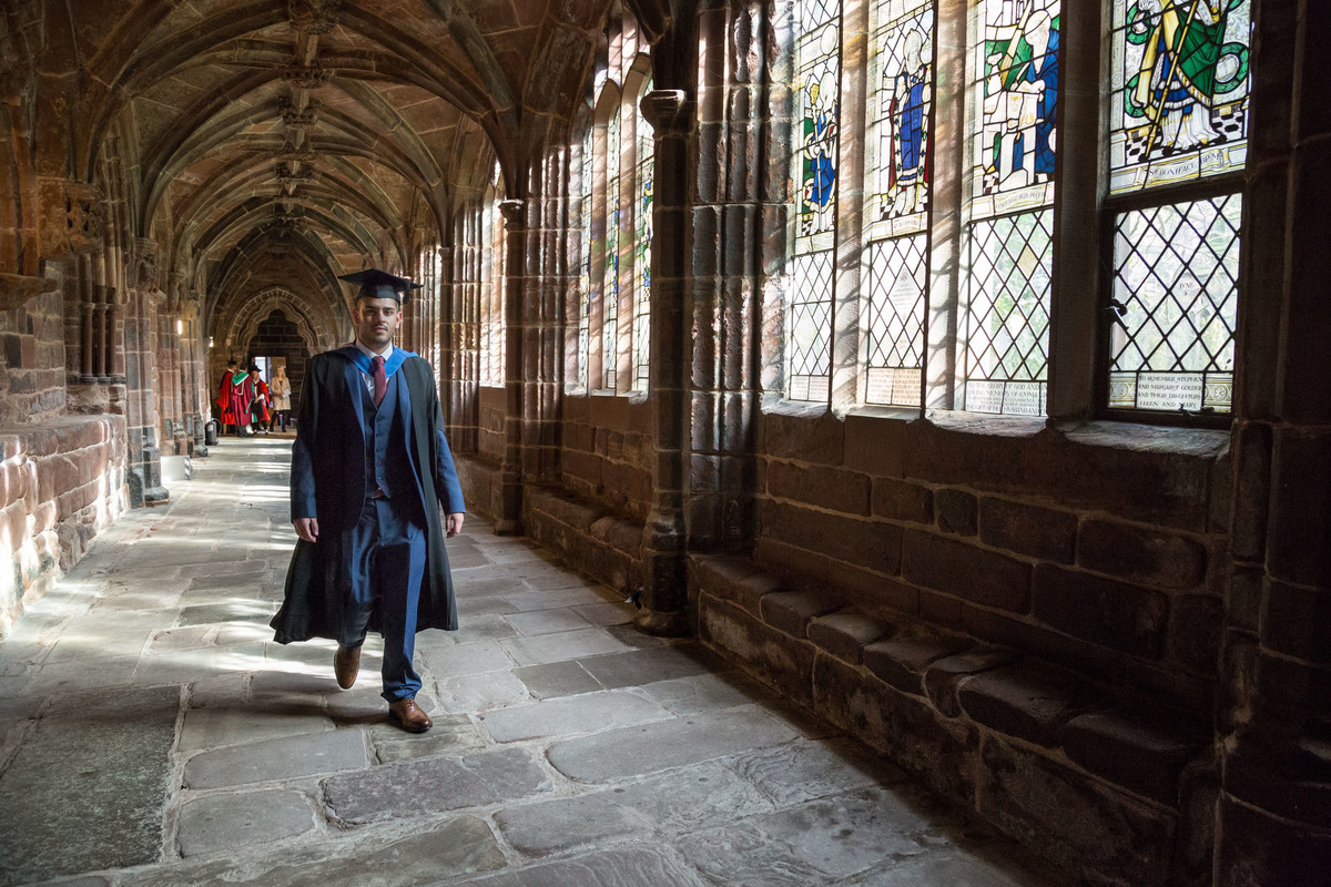 Graduate walking through cathedral grounds wearing formal cap and gown