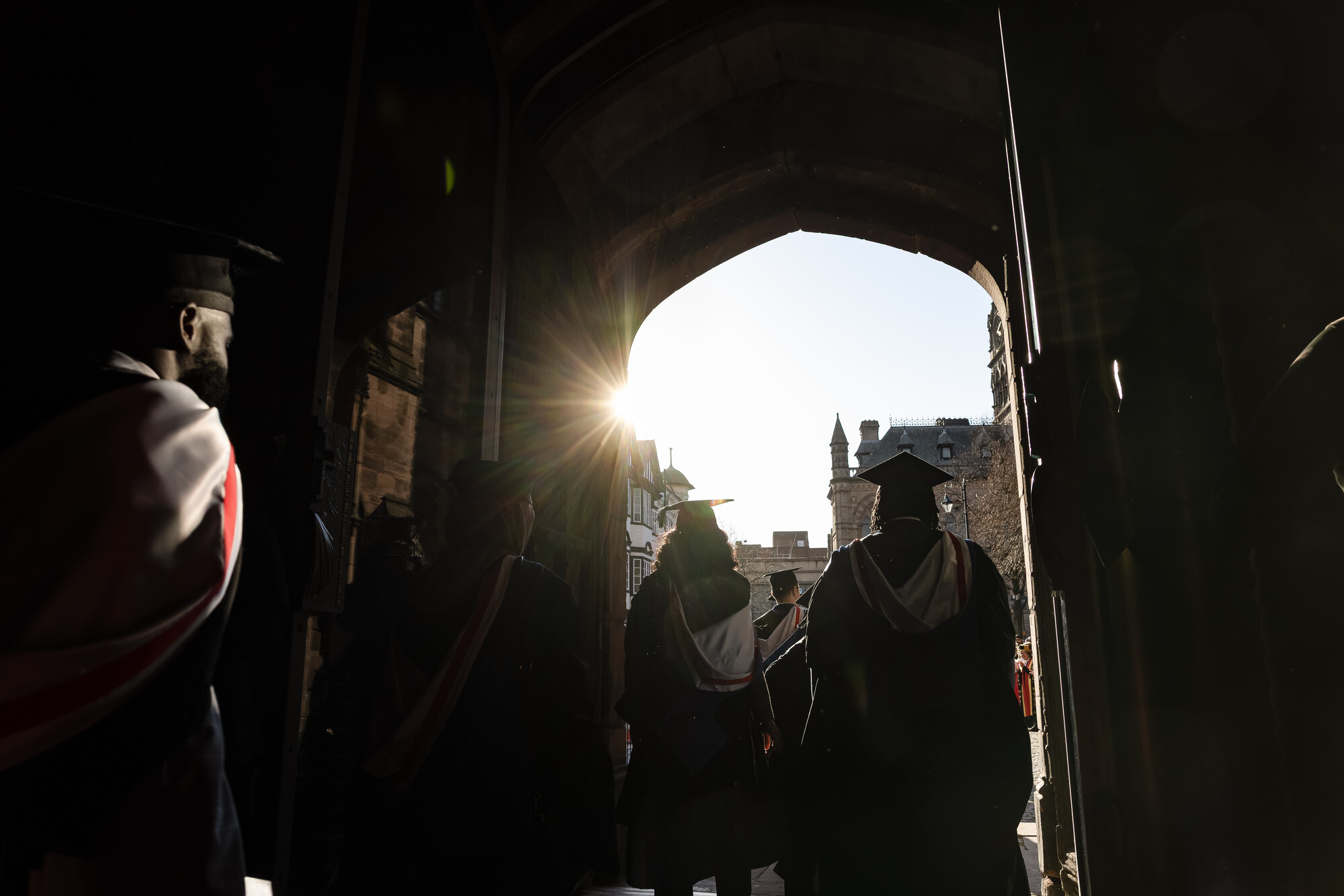 Graduates walking through Chester Catherdral entrance, into the sunlight
