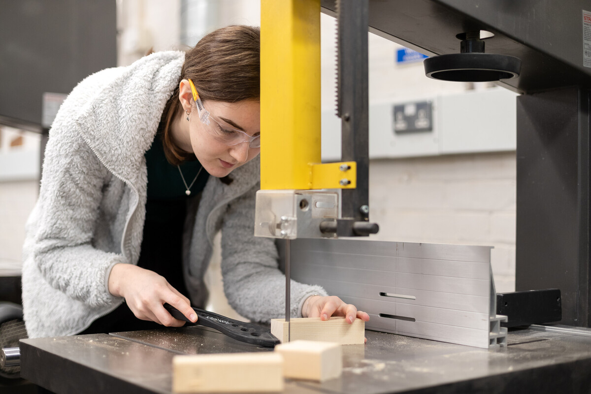 An art student using a technical edge cutting machine tool on wood..