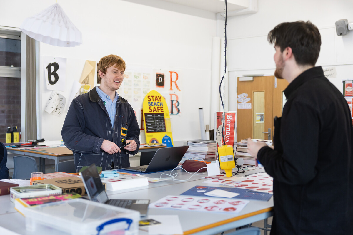 Graphic design studio where two students are talking over their exciting work