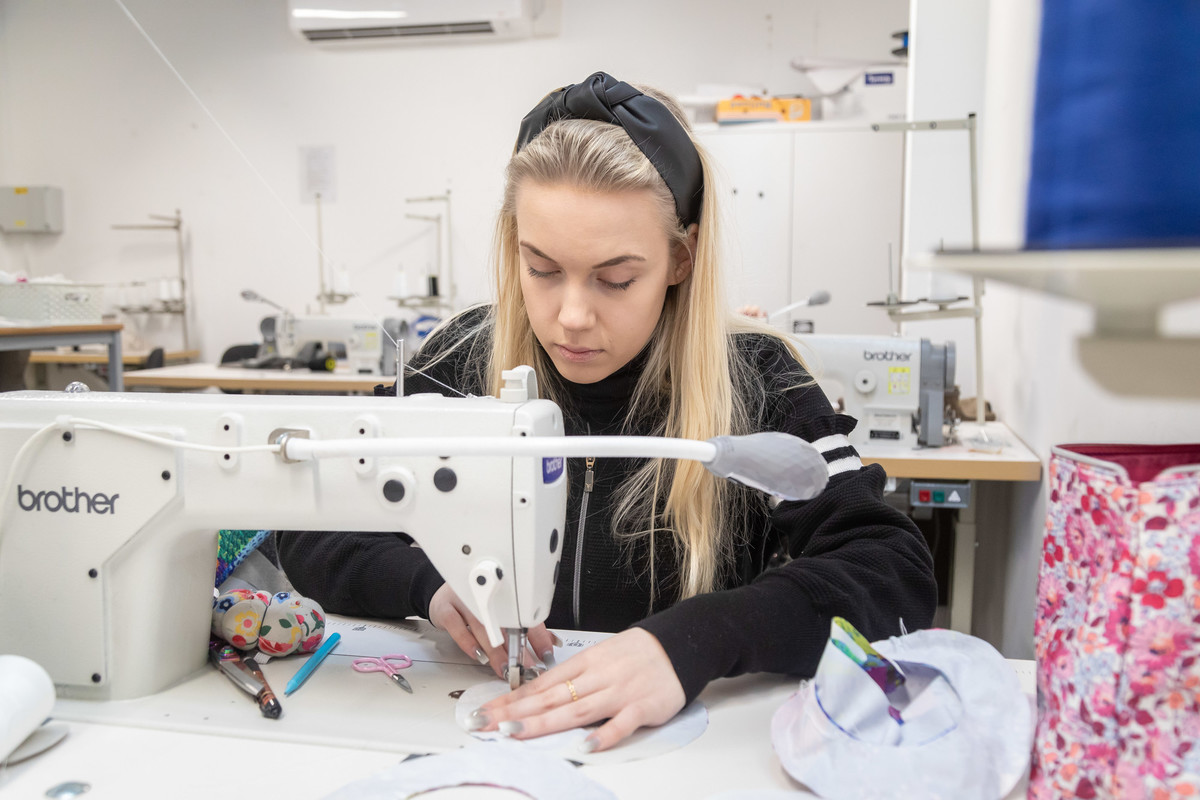 A student working on a sewing machine in a design studio