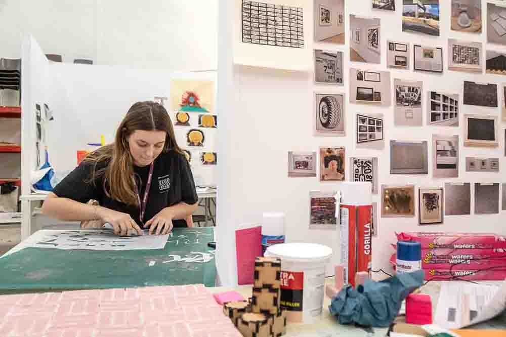 Art and  Design female student in art studio workspace with various art materials.