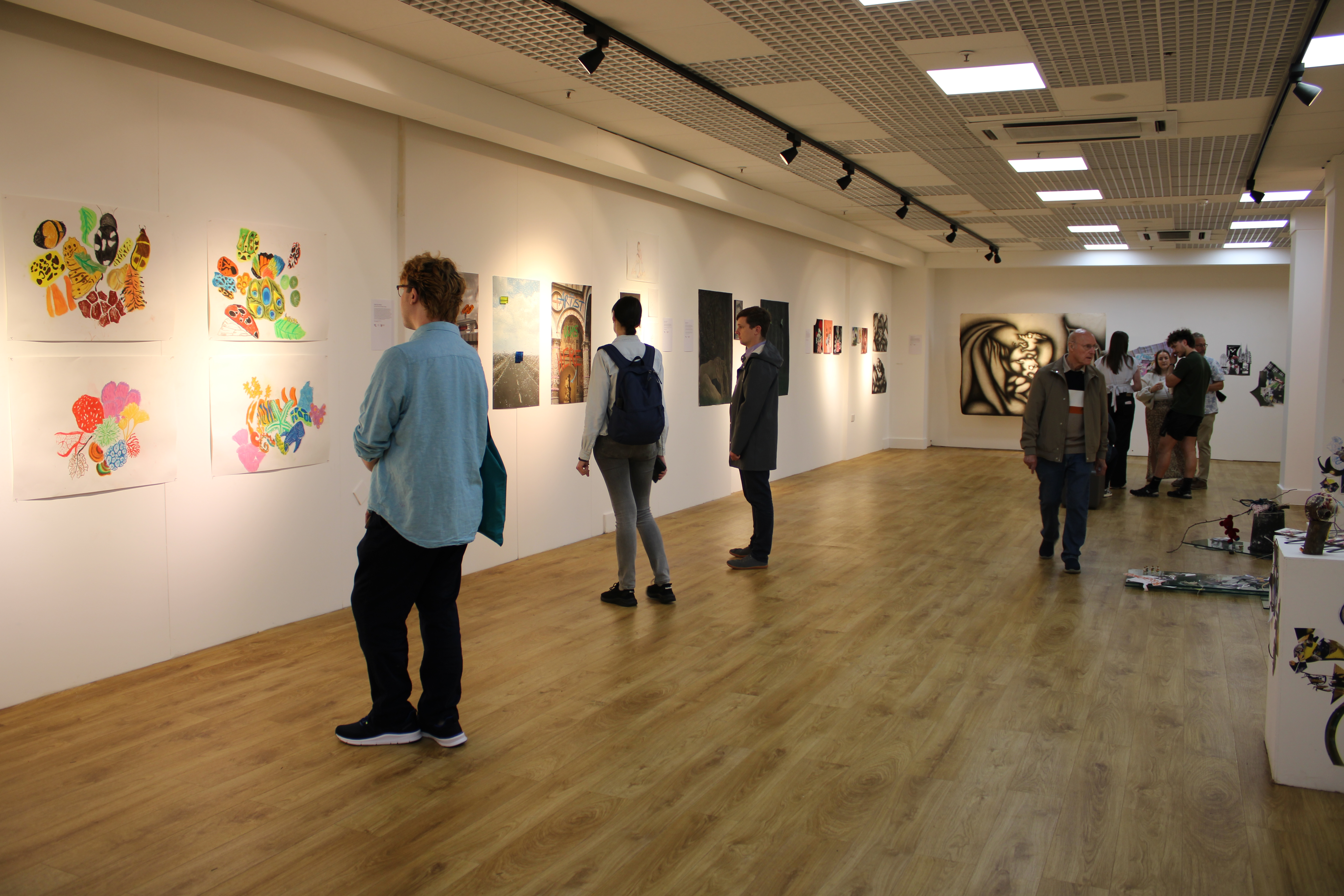 People looking at art pieces inside of gallery