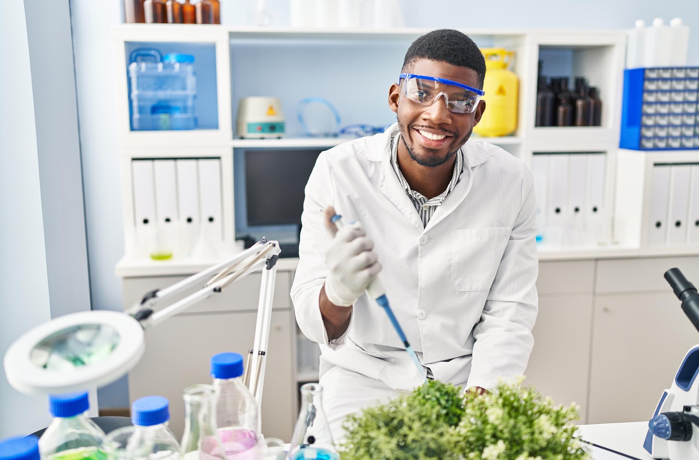 BSc zoology student wearing scientist uniform using pipette on plant at laboratory