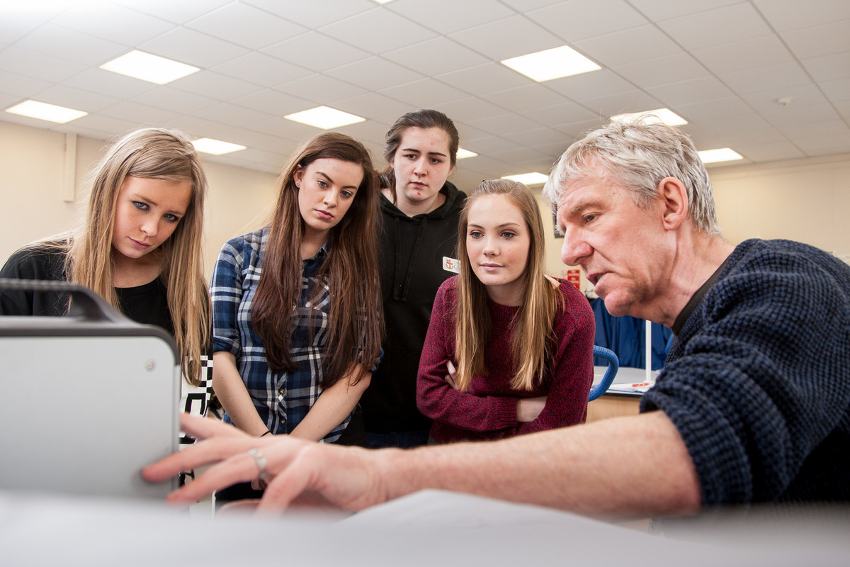 A group of students and tutor  looking at computer screen while doing some research in a laboratory.