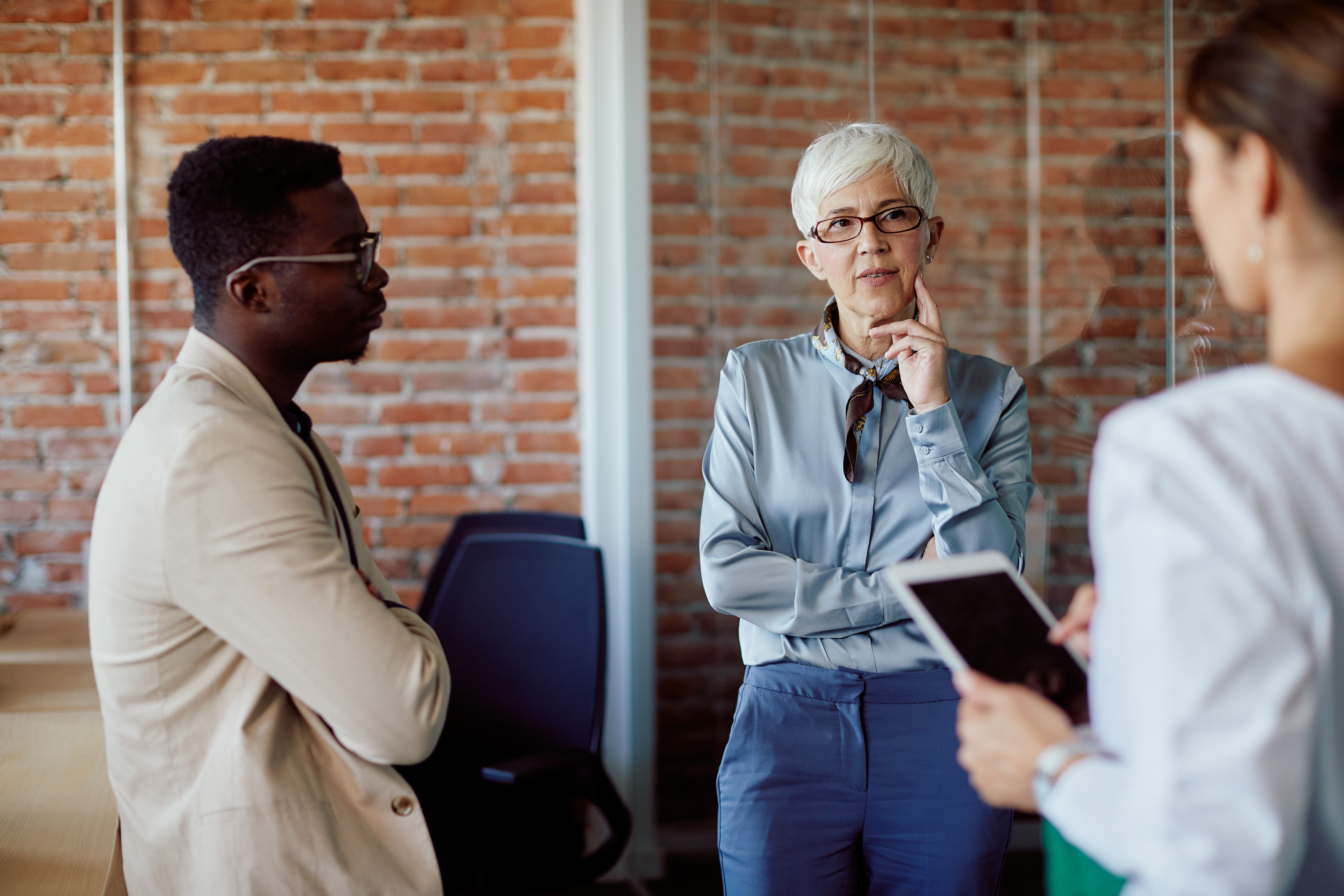 Mature managing director talks to her team during business meeting at corporate office.