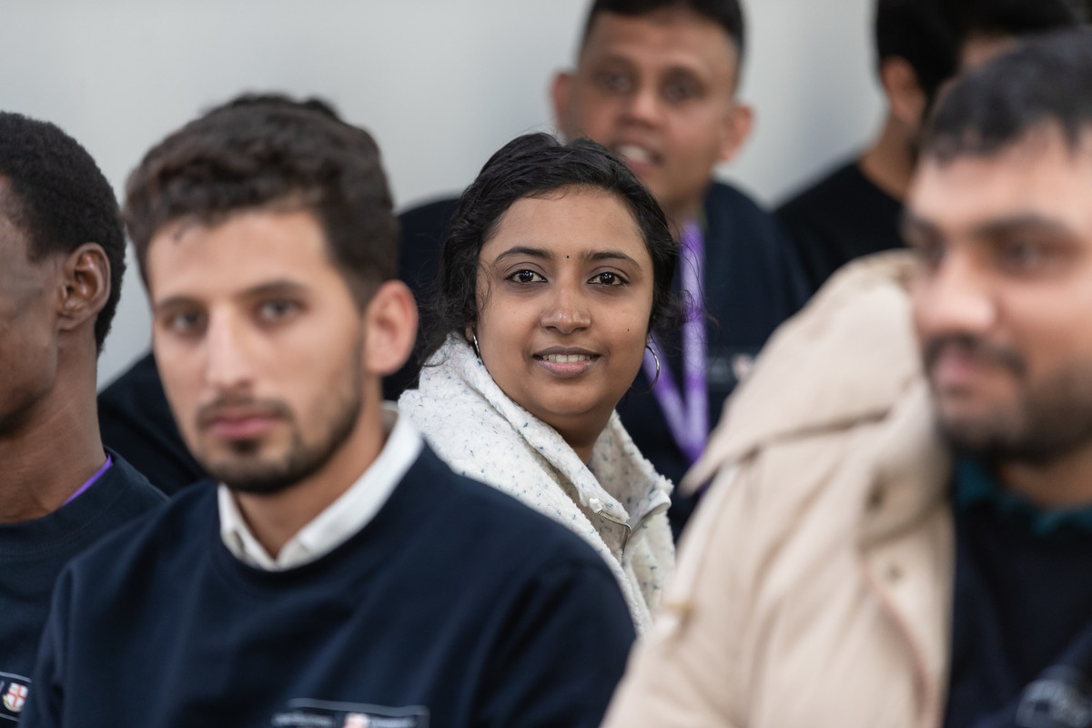 A smiling happy group of male and female international students, attending an induction on Queen's Park campus.