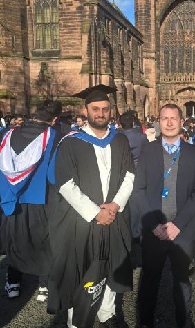 Fazale wearing a graduation cap and gown outside Chester Cathedral