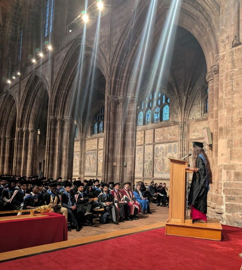 Ravina delivering a speech on the graduation stage in Chester Cathedral