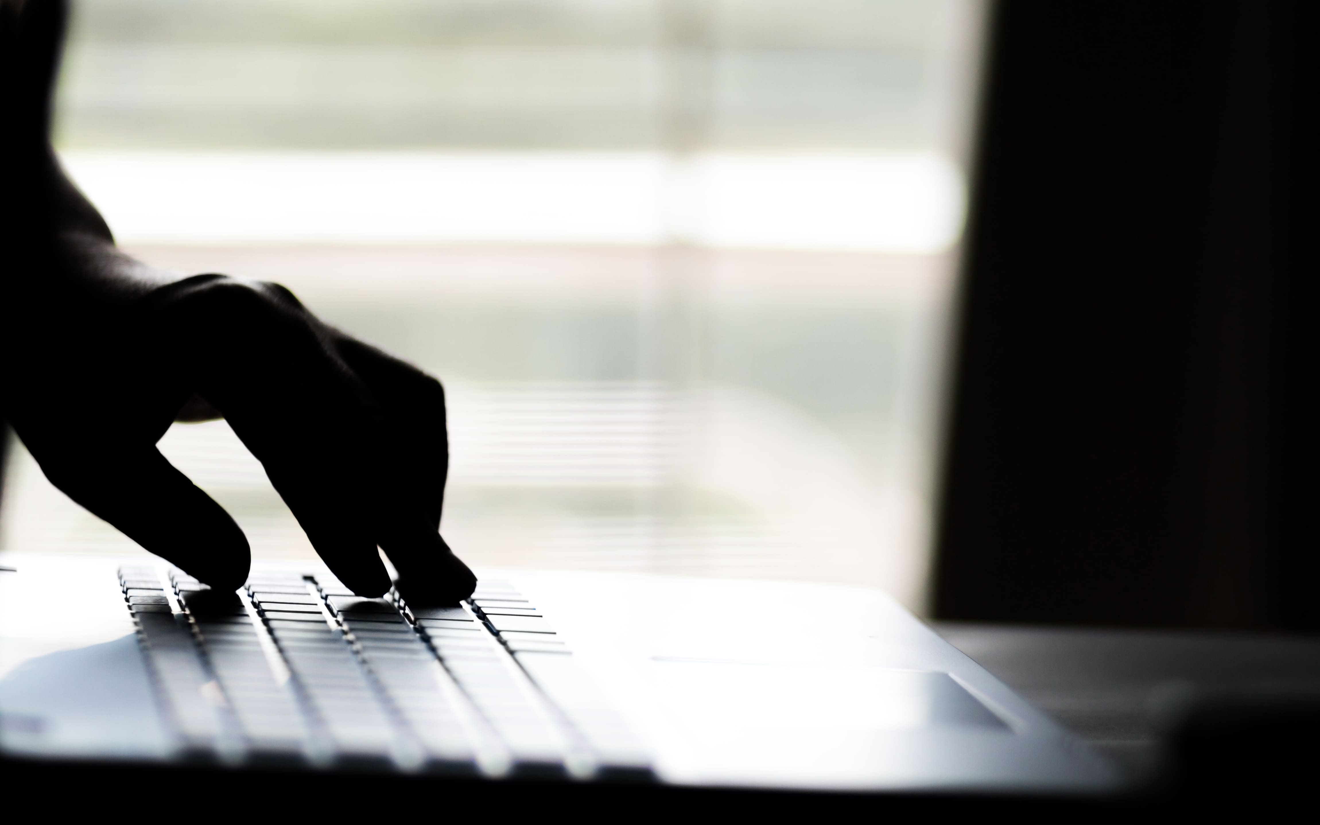 black and white close up of hands on a laptop keyboard