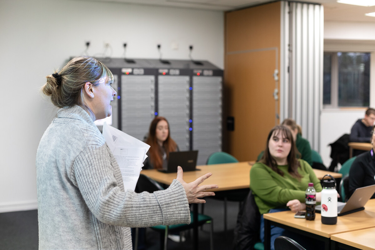 A group of students sat in a lecture with a teacher