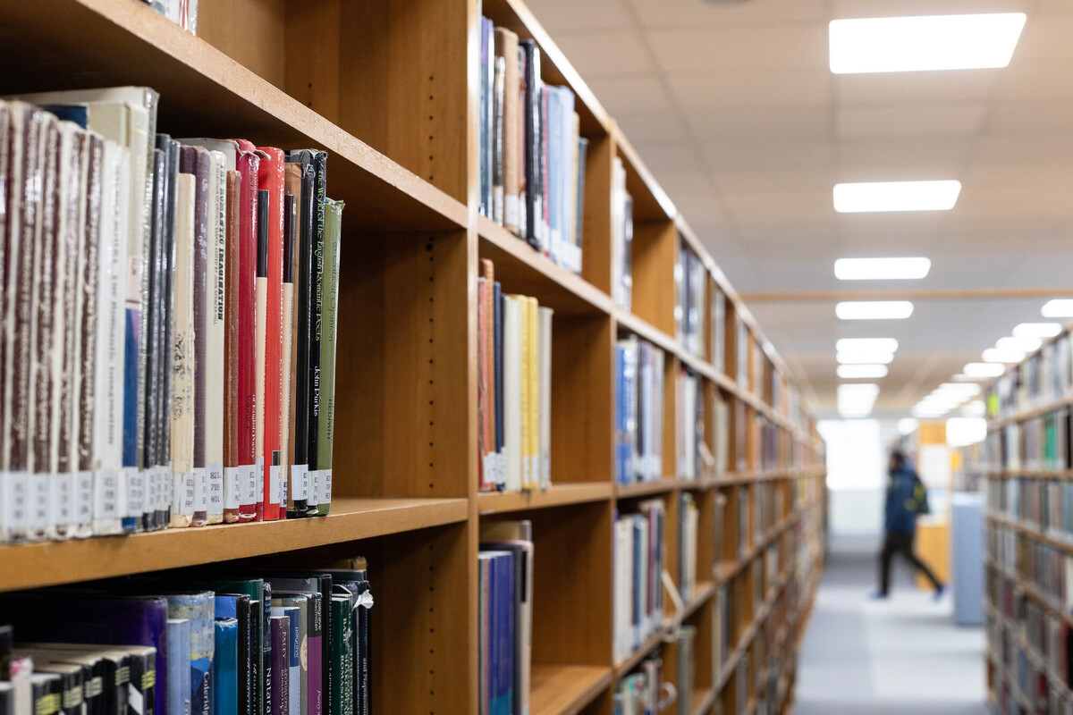 Library room with rows of wooden book shelves.