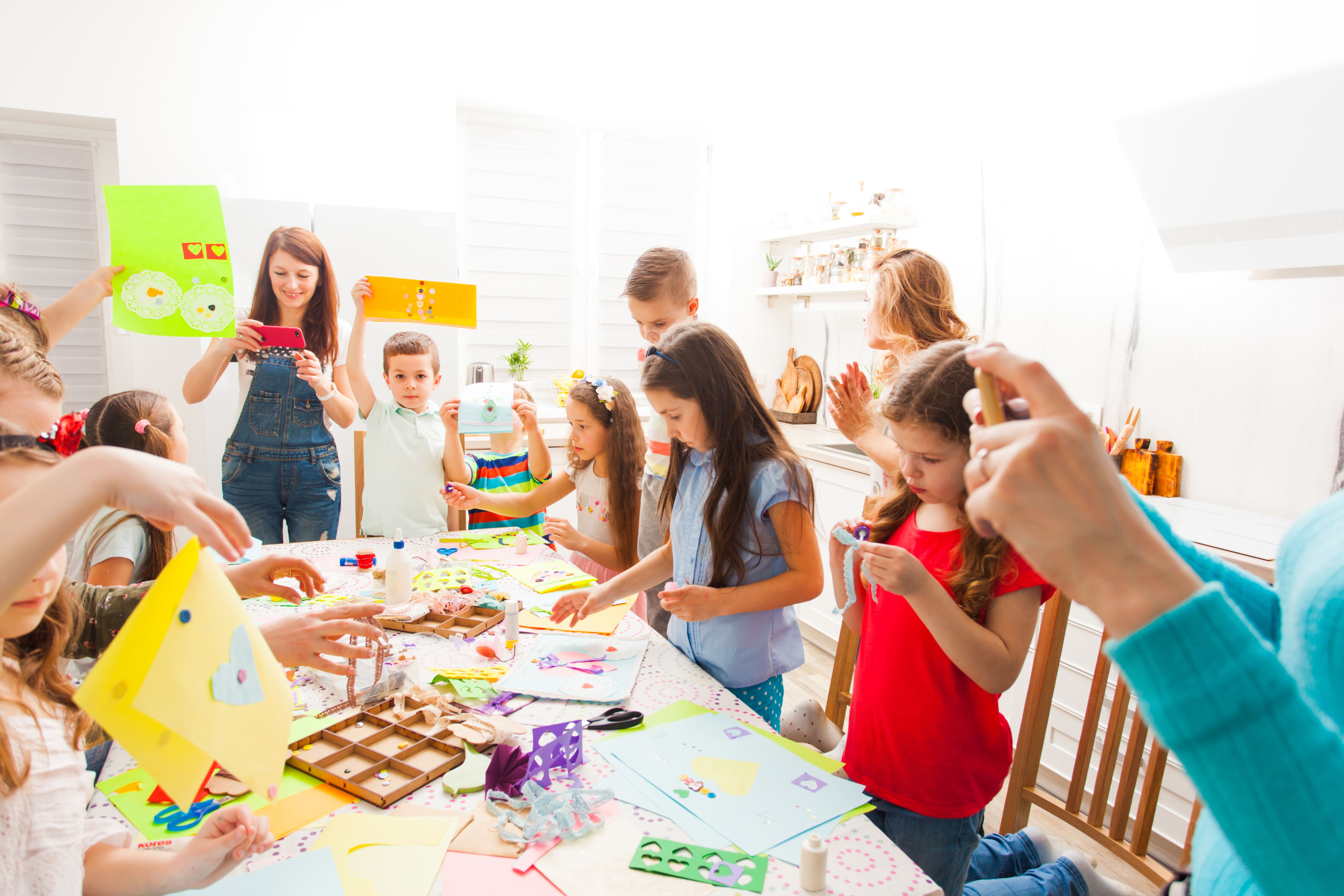young children doing craft activities around a table with an adult supervising