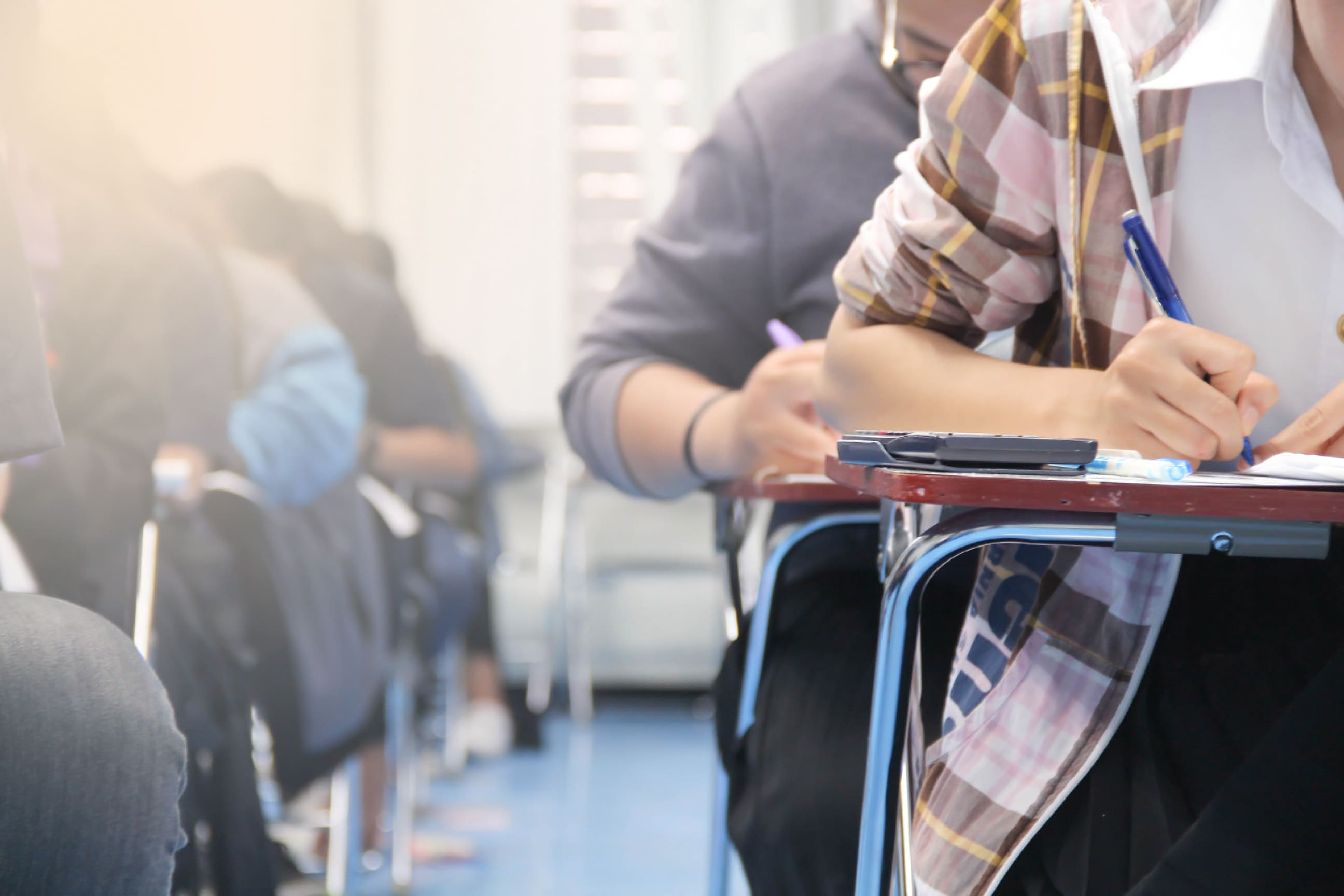 students writing at individual desks in exam conditions