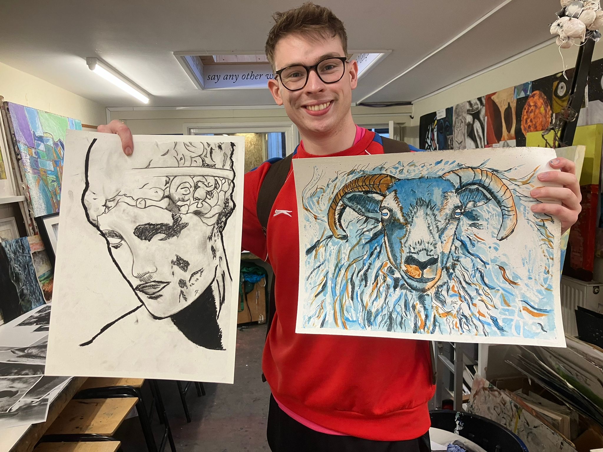 A man holding up two art sketch and painting pictures.