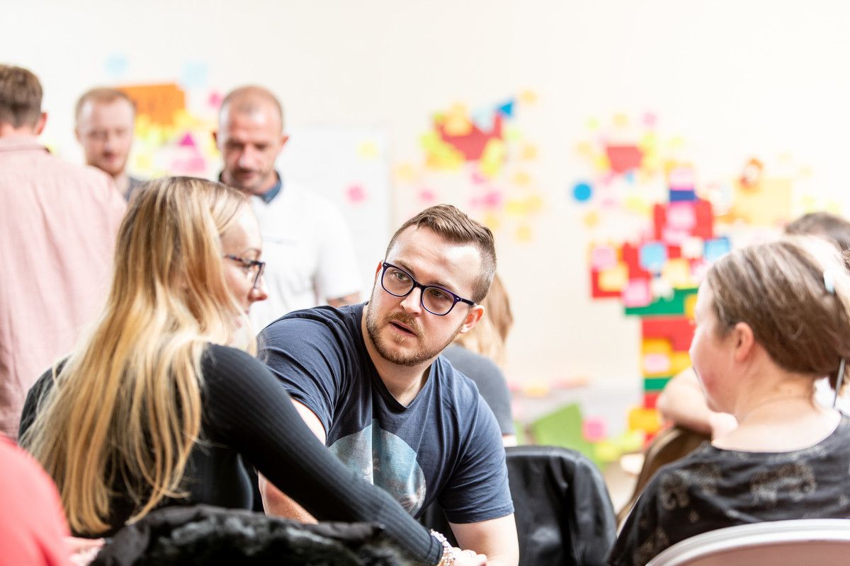 A group of students in a teaching room with colourful artwork on the wall.