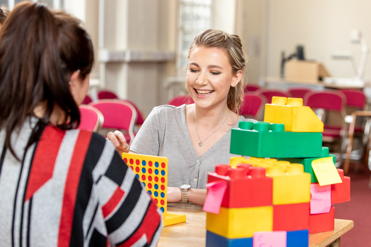 Two female student teachers in training classroom setting.