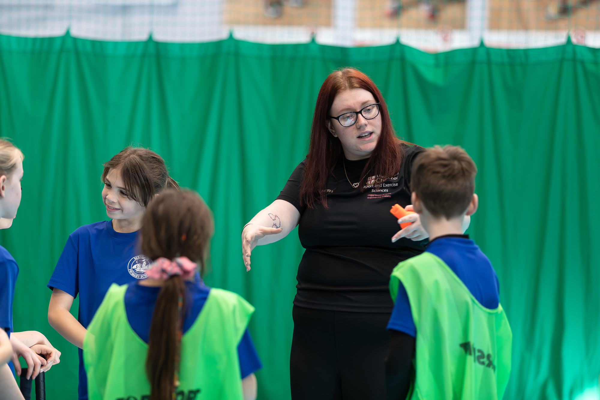 A female coaching  primary school children in PE class.