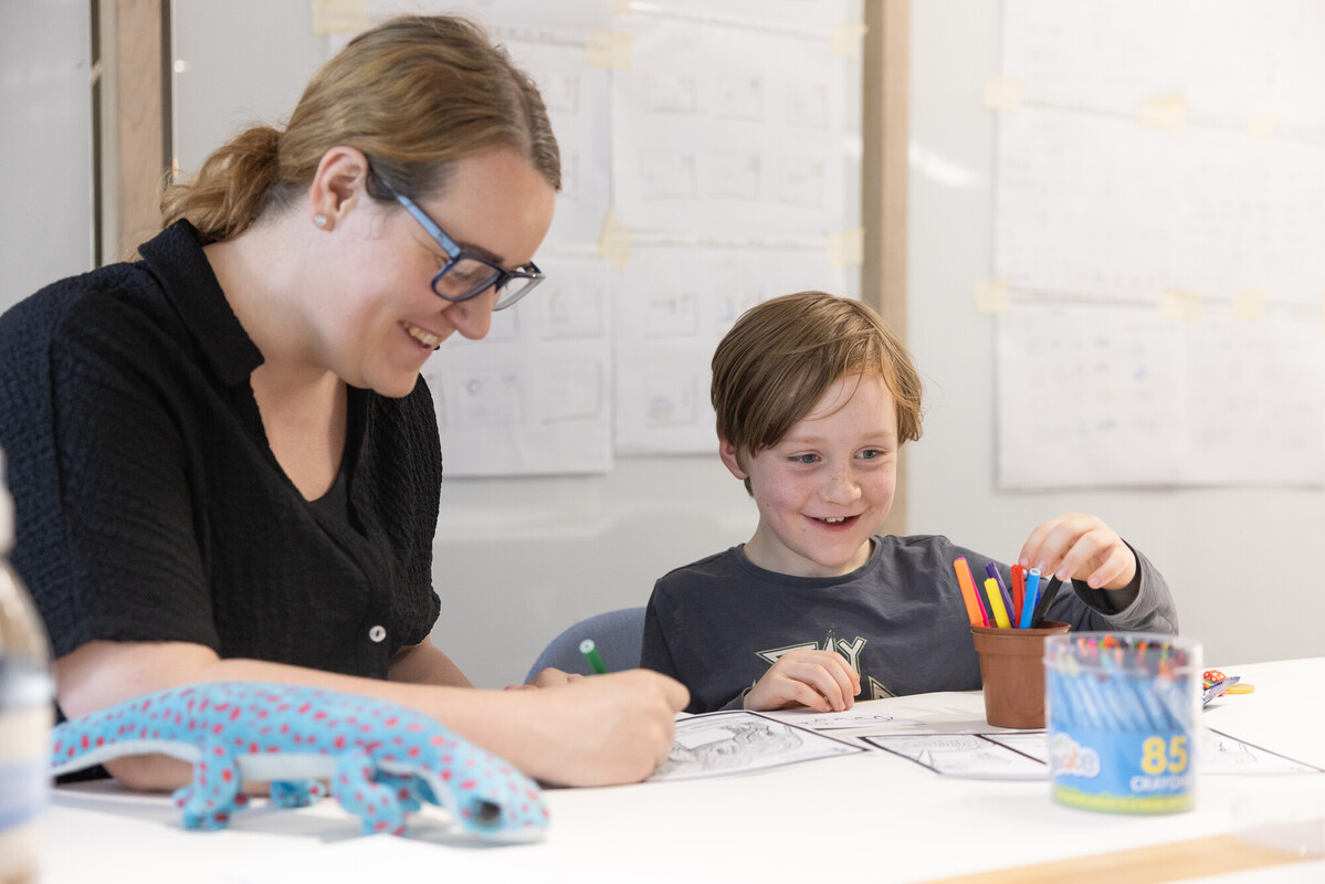 A woman and a child are seated at a table with markers, showcasing creativity in an Early Years PGCE context.