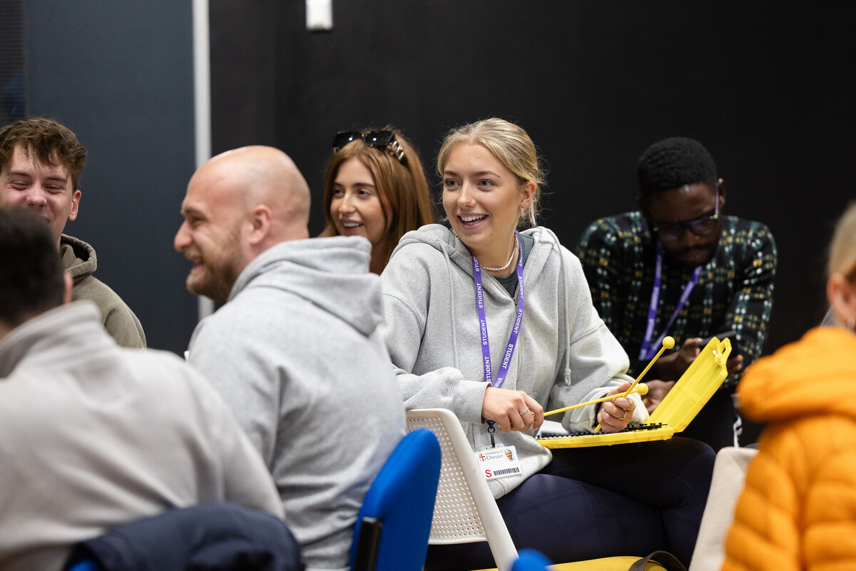 A group of smiling individuals seated in chairs, engaged in a discussion about the Early Years PGCE with QTS program.