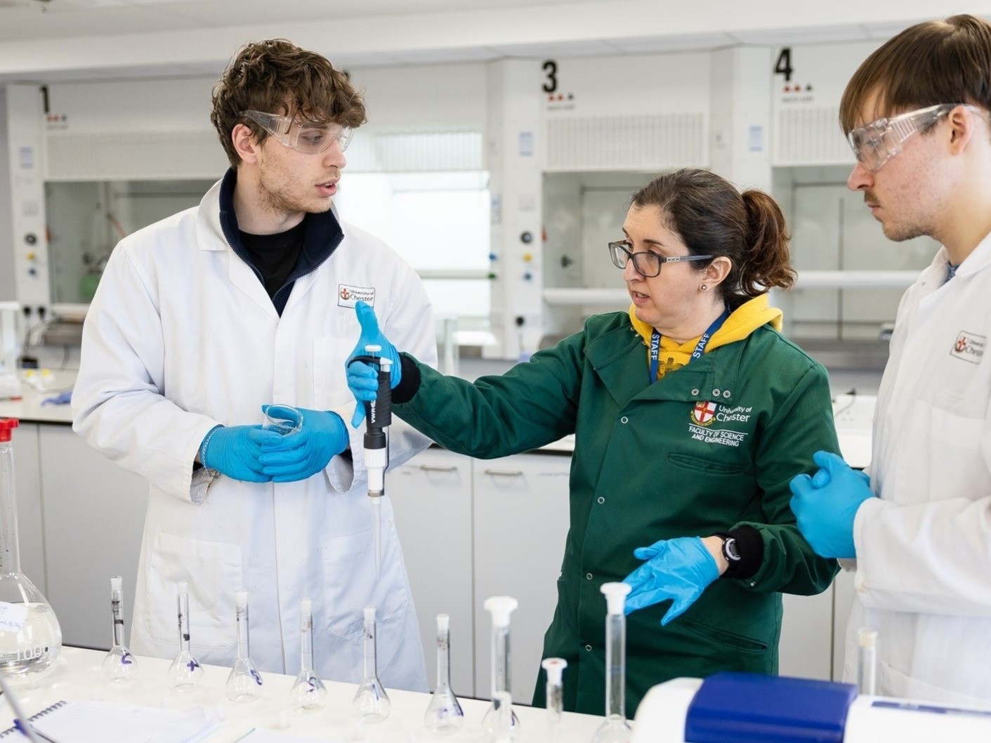Three students working with laboratory equipment.
