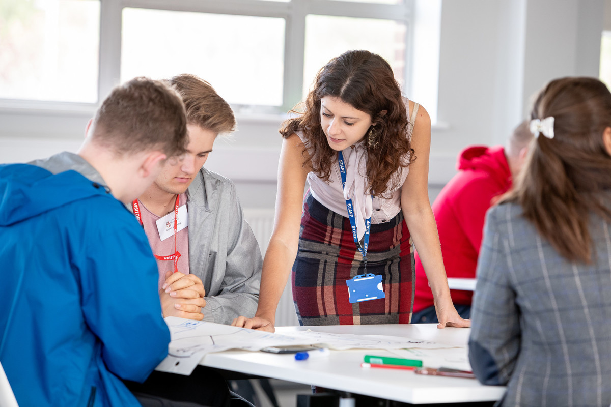 Staff member helping two students at a desk