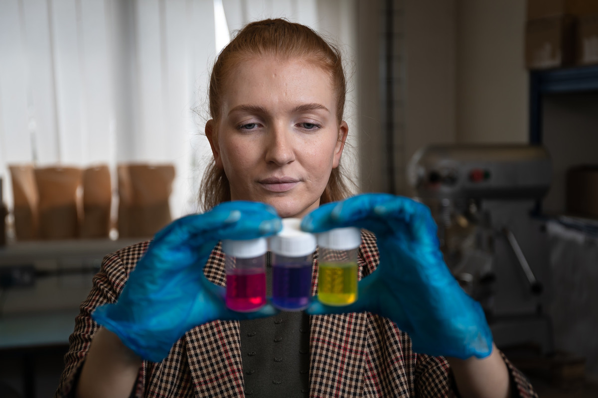 A Woman wearing gloves looking at chemical solutions in beakers
