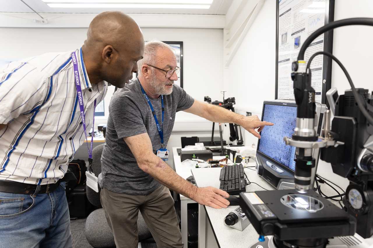 Two men doing research work looking at open computer screen.