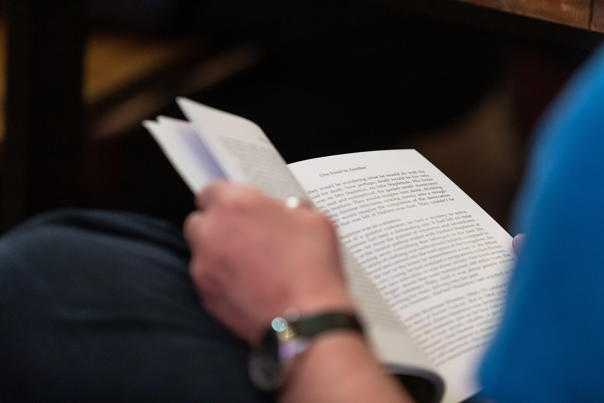 A partial view of an open book and a hand holding it.