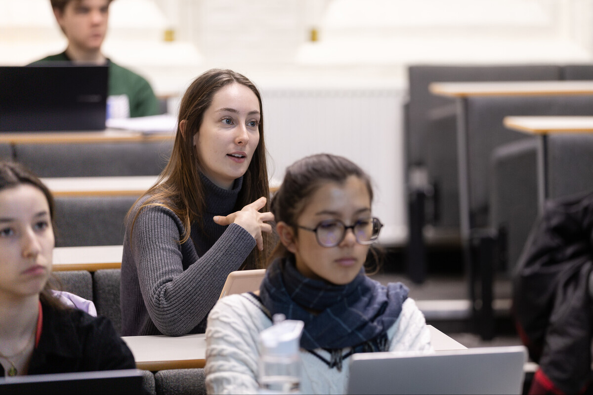 two students sitting in rows behind each other in a lecture theatre