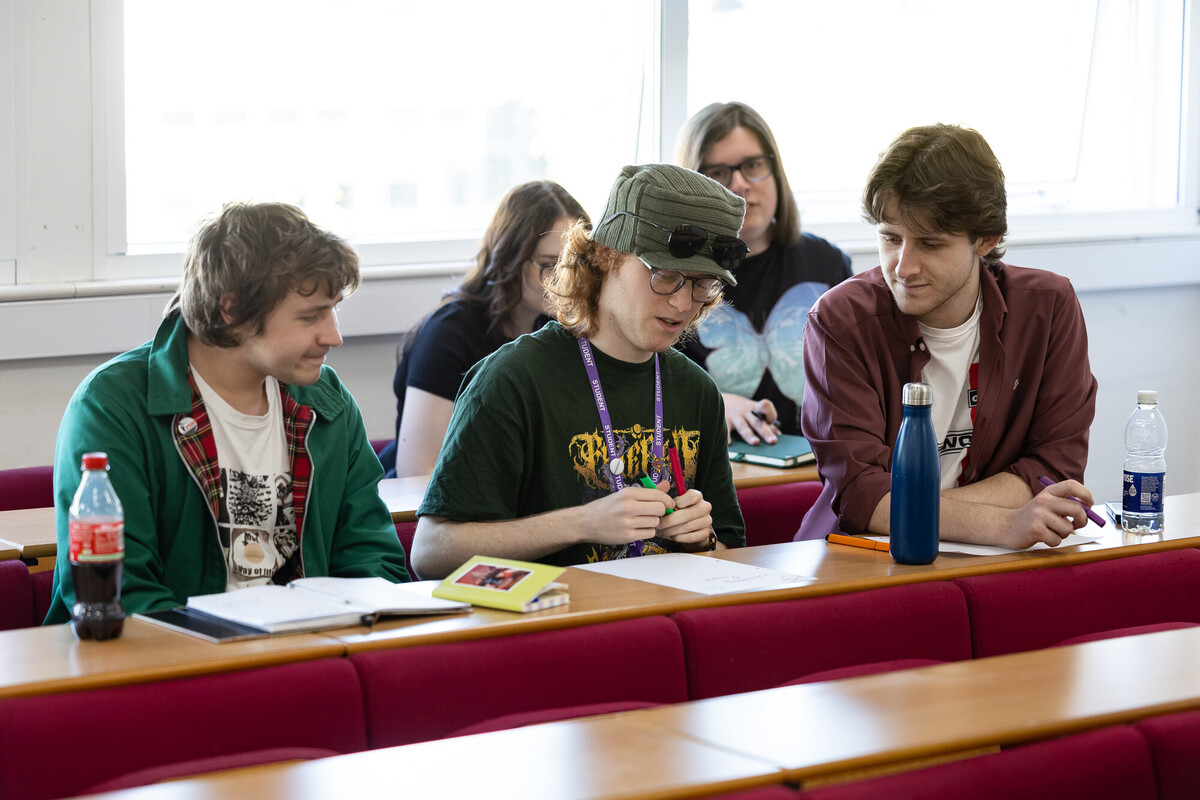 Students sit at desks in a university lecture room working.