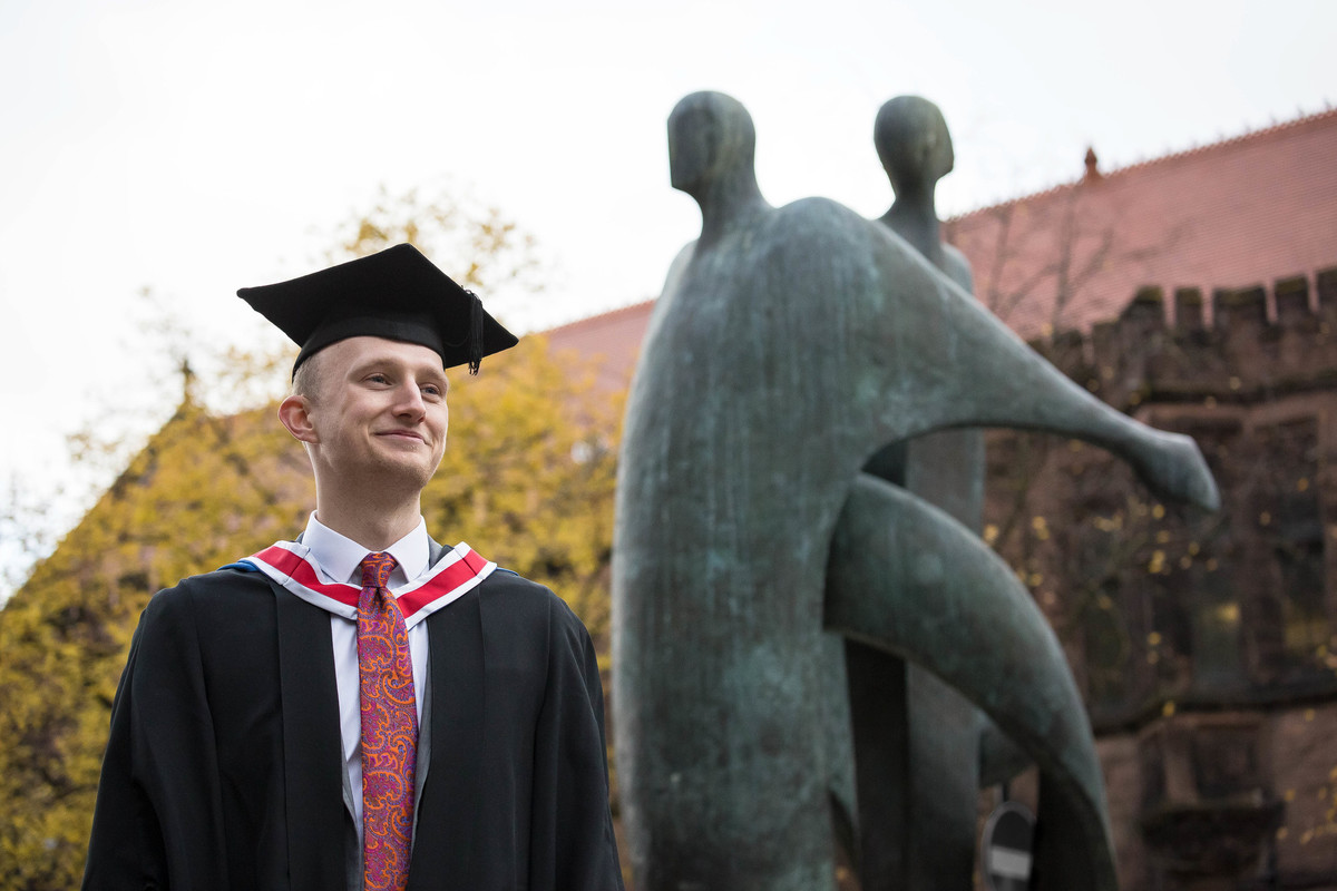 A person stands in graduation clothing