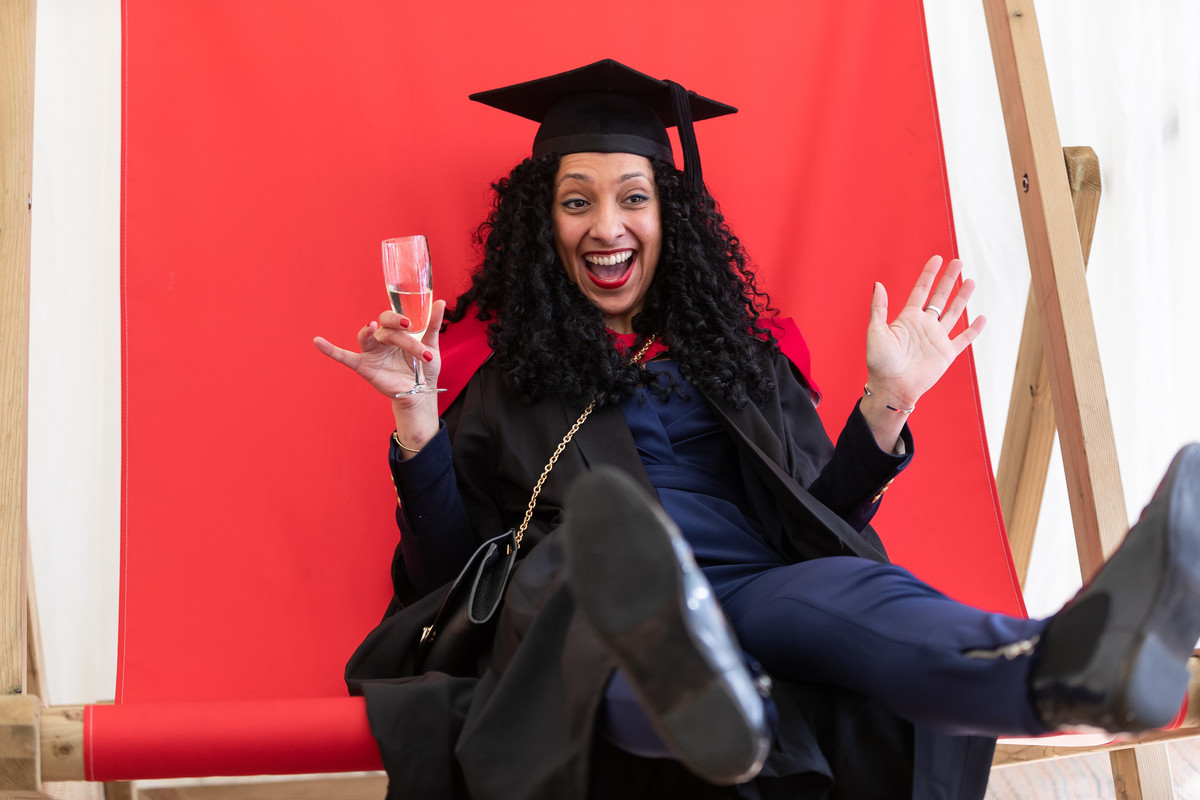A person sits in graduation clothing in a chair