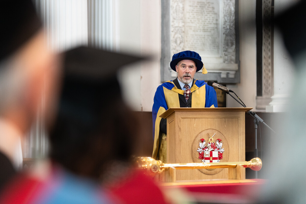 A person speaking at a lectern during graduation ceremony