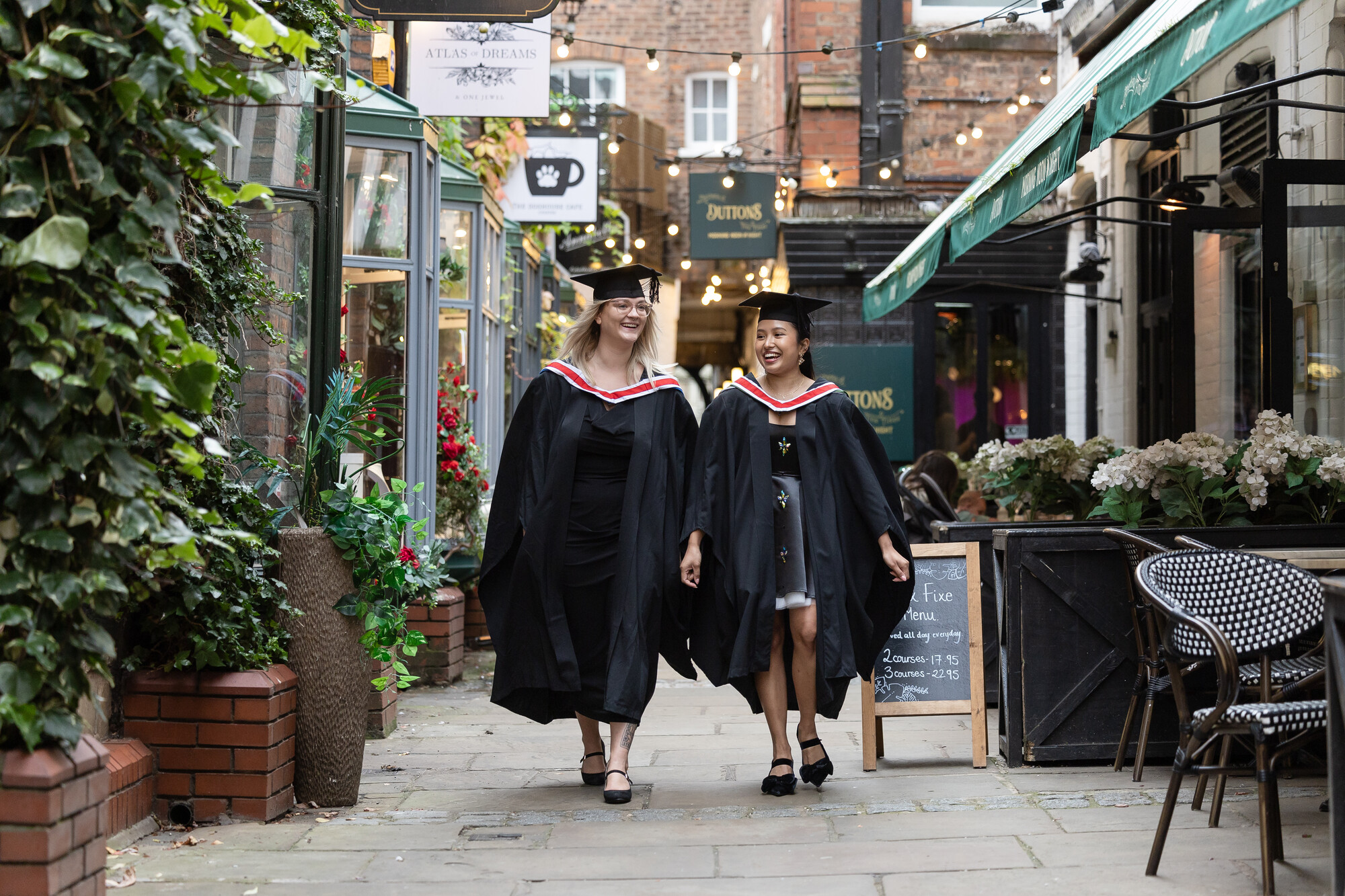 Two University of Chester graduates in gowns walking confidently, reflecting the employability skills and career prospects gained through their degree.