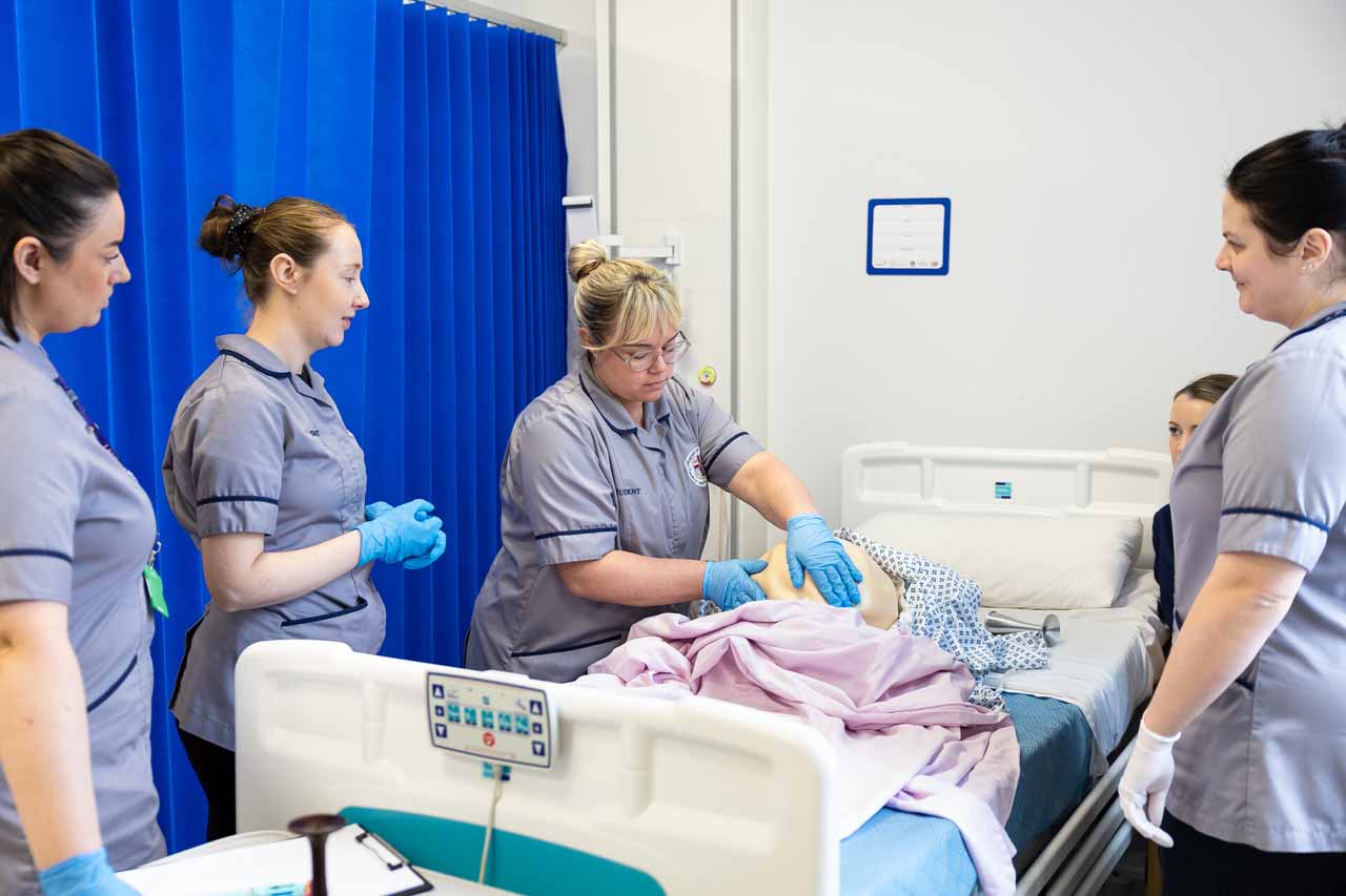 A group of female nurses in ward simulation midwifery training session.