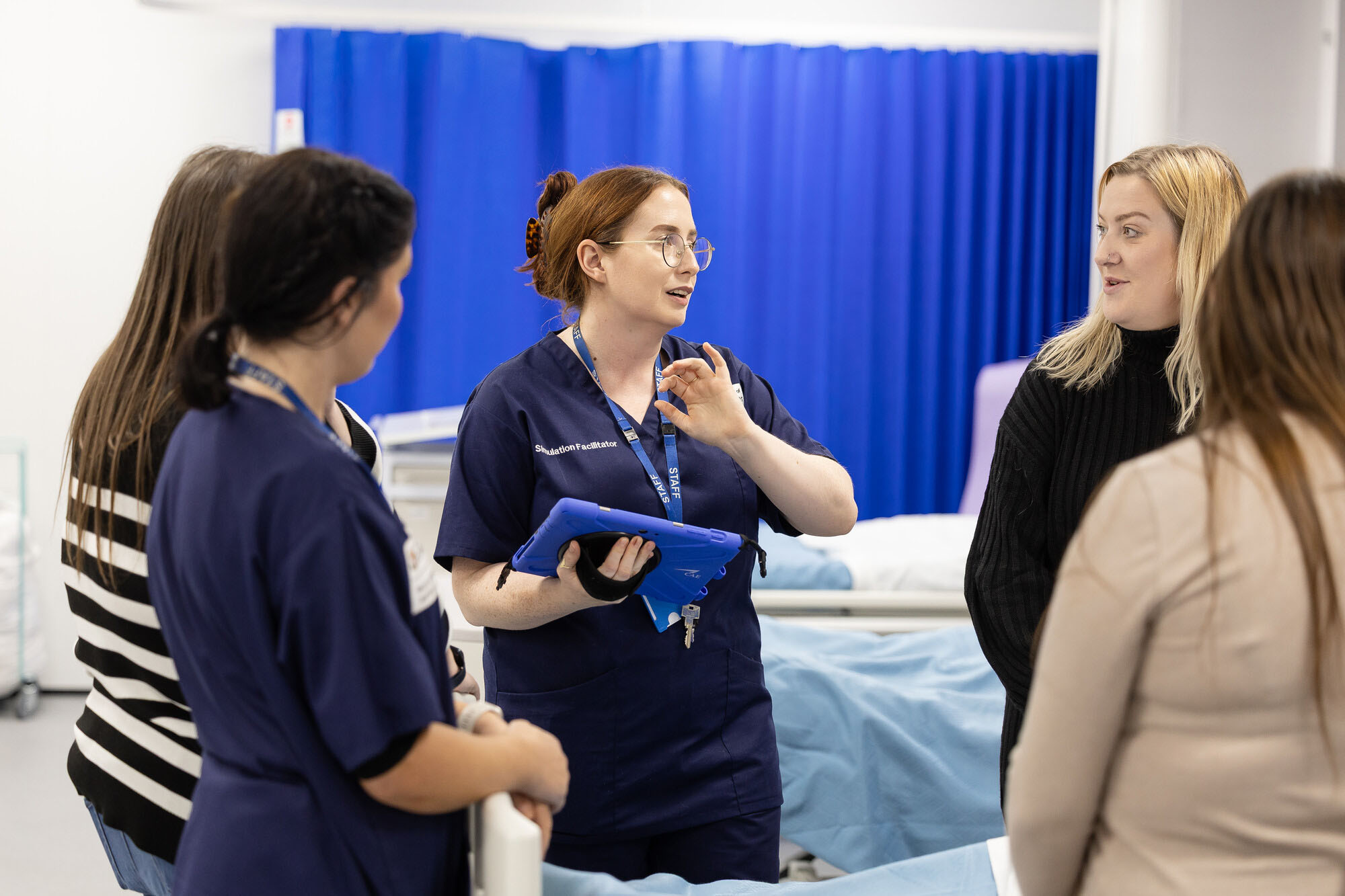 Healthcare tutor guiding students through a practical nursing skills session in a simulated clinical environment at University Centre Birkenhead.