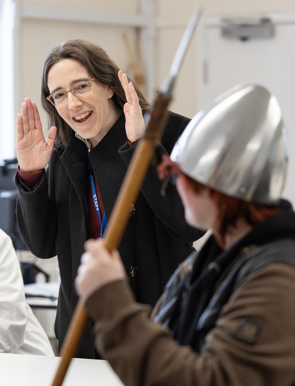 Dr Morn Capper with a student demonstrating archolgical artifacts, a helmet and spear