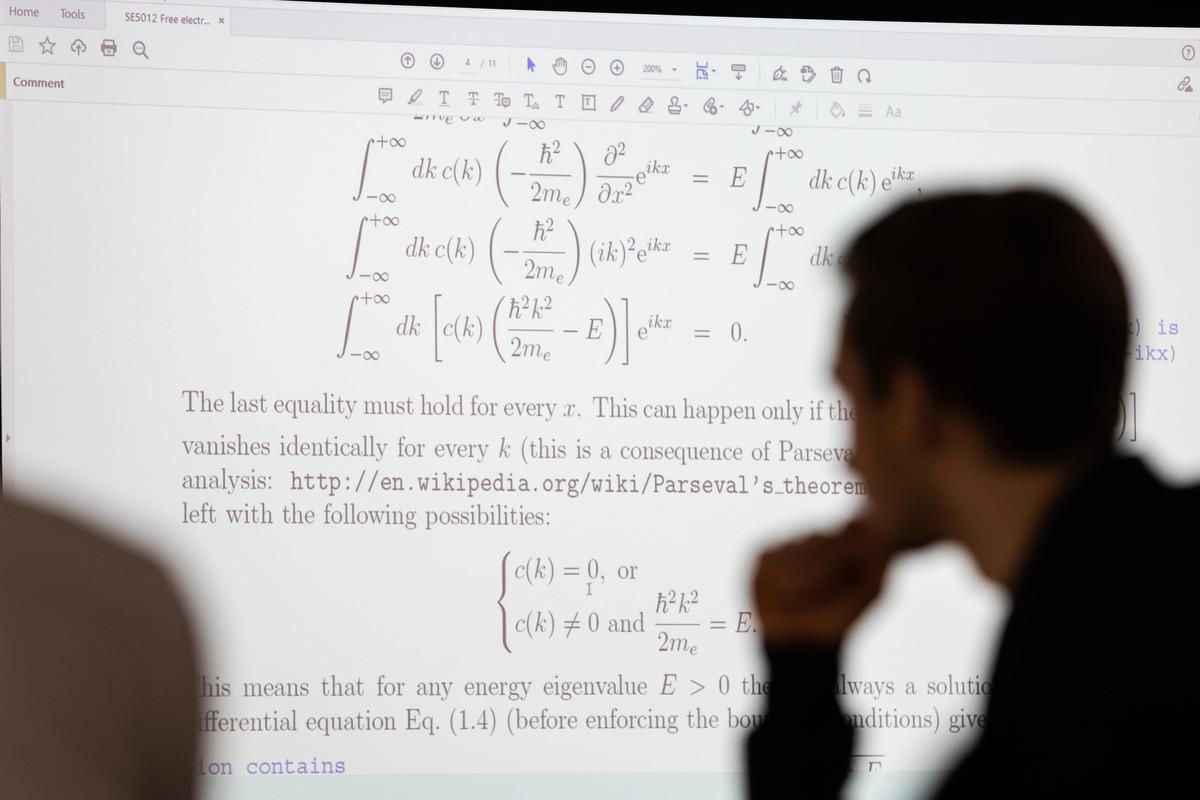 Students studying advanced mathematical concepts during a classroom presentation, with equations and mathematical analysis displayed on a screen. Image representing the Mathematics Education at the University of Chester, focusing on mathematics teaching, curriculum development, educational research, and professional practice.