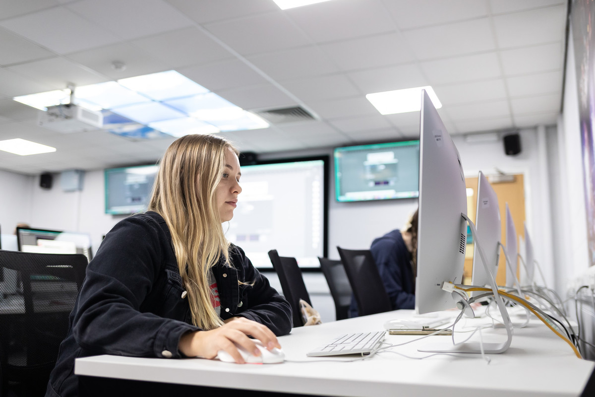 A media student working at desk and computer screen.