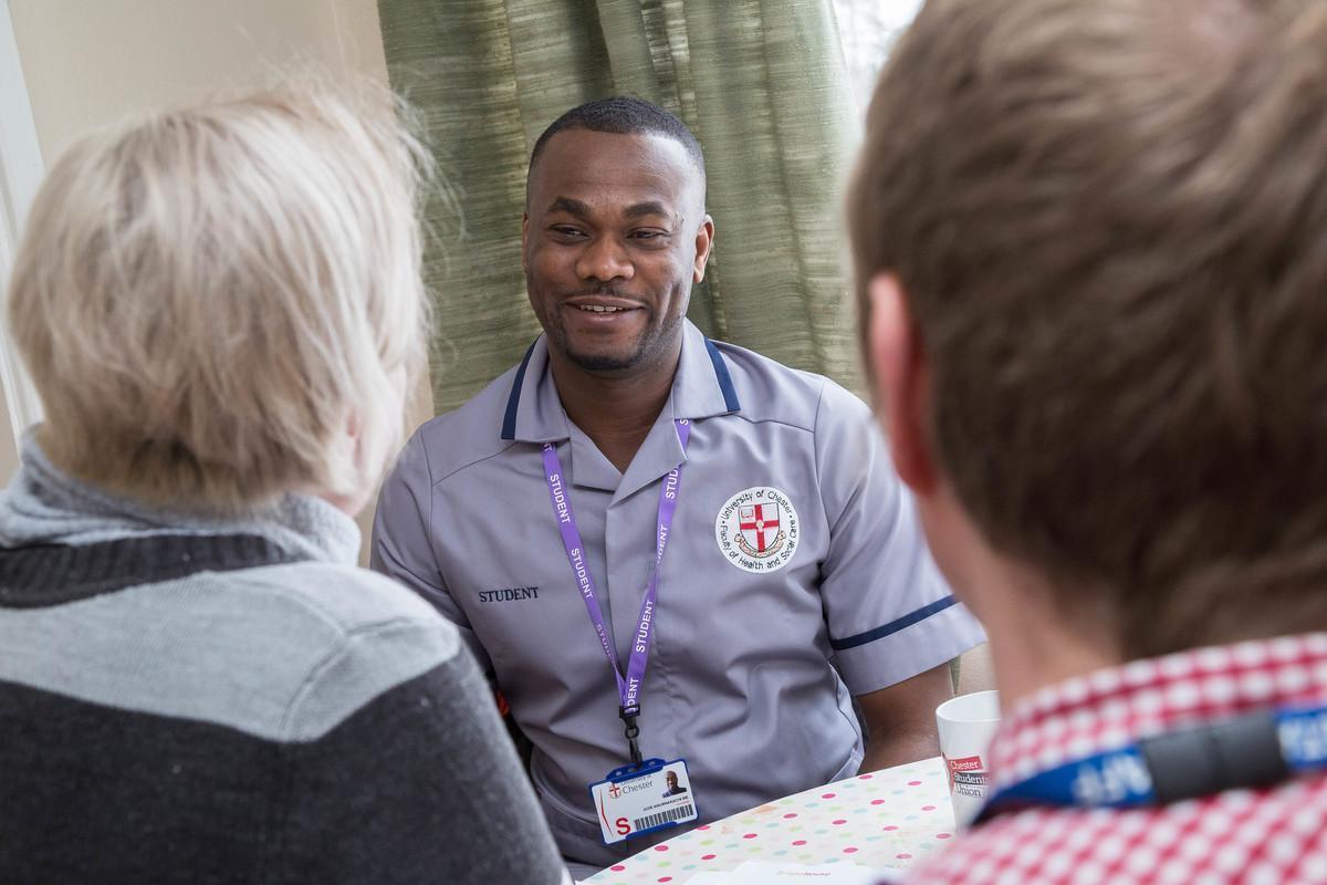 Mental health nursing degree student smiling and talking with two people, showing supportive and compassionate care.