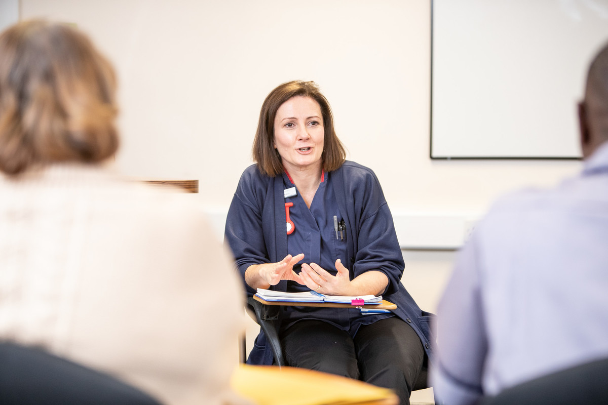 woman in uniform talking to other people in classroom