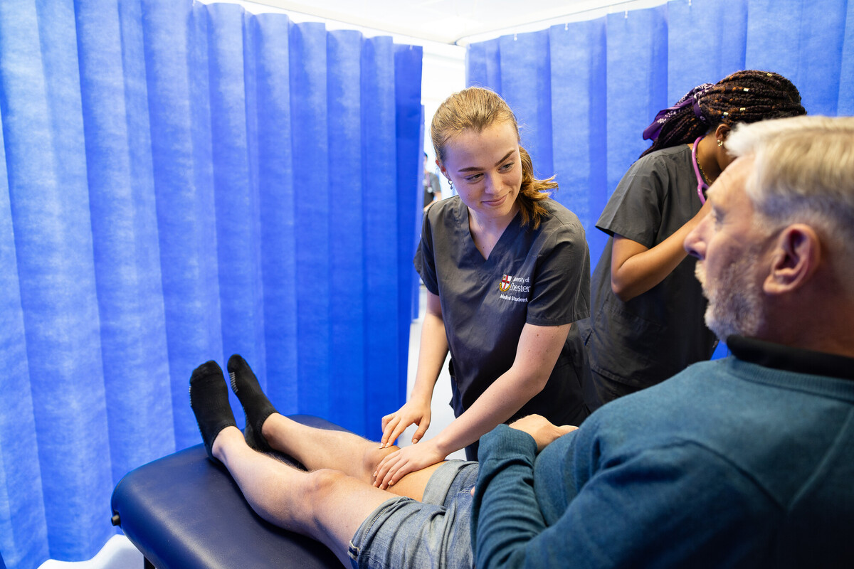 Chester Medical Student examining the knee of an older male patient lying on an examination bed.