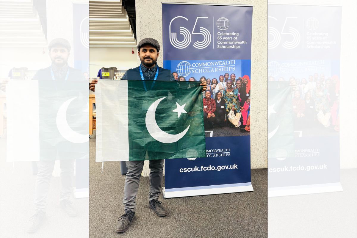 A man holding the flag of Pakistan, looking at the camera.