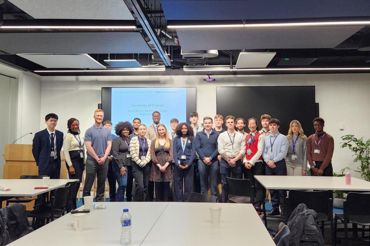 A group of people lined up in a row, looking at the camera, in a classroom.