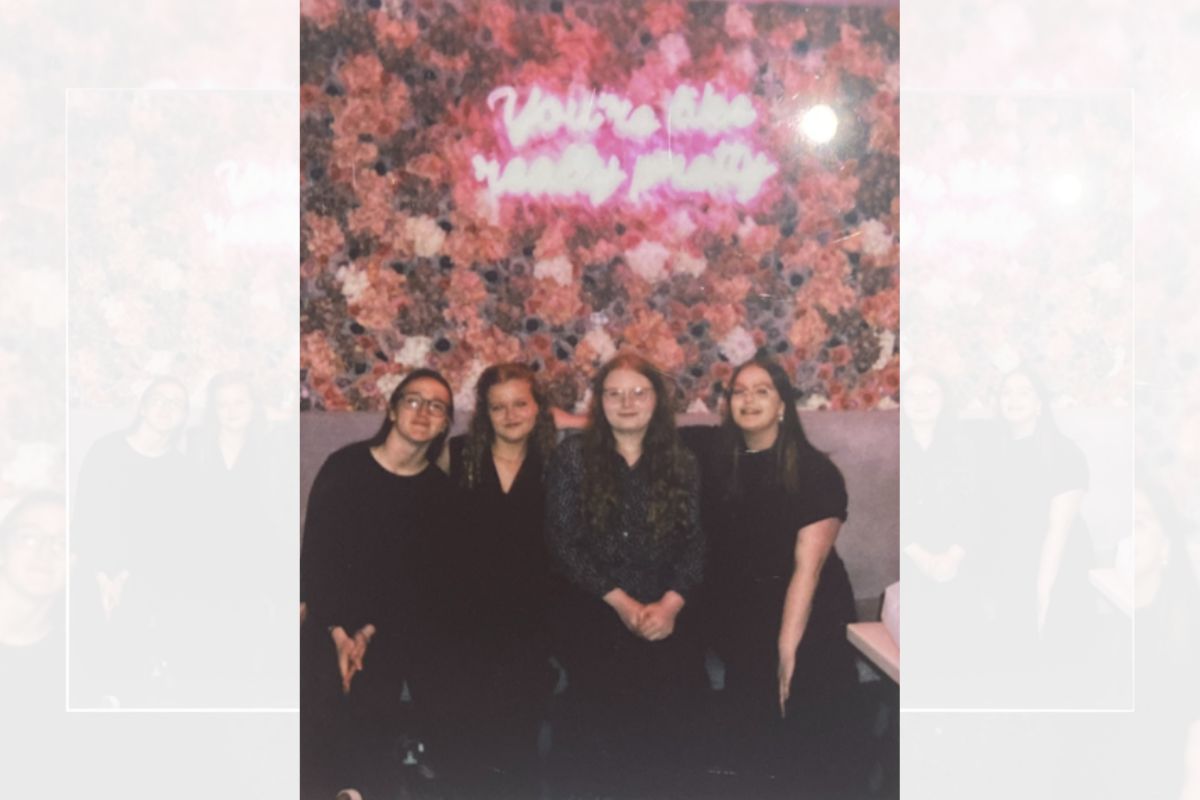 Four students sat down on a chair. The photo is filtered to a 1990s Polaroid style.