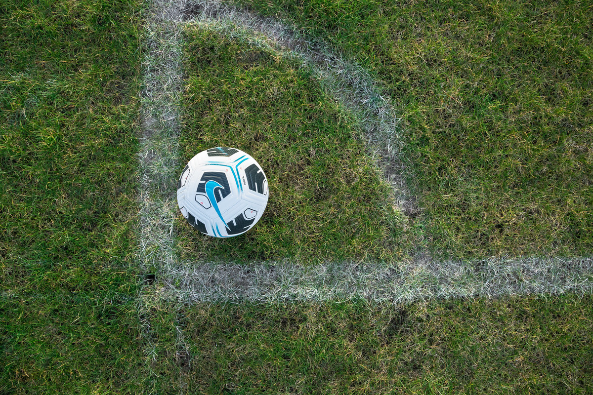 A football on the corner of a pitch, viewed from above.