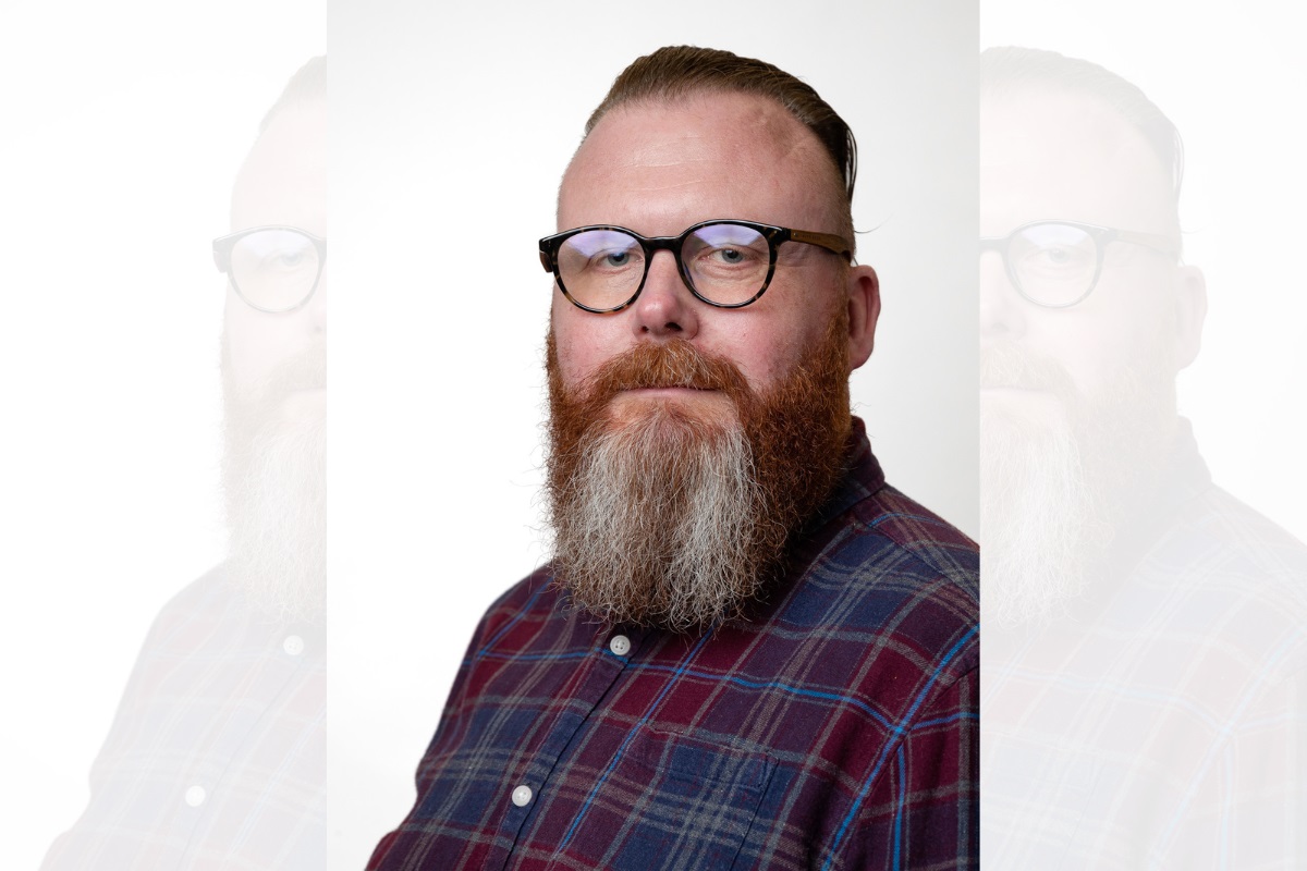 A head-and-shoulders photo of a man with glasses and a beard looking at the camera.