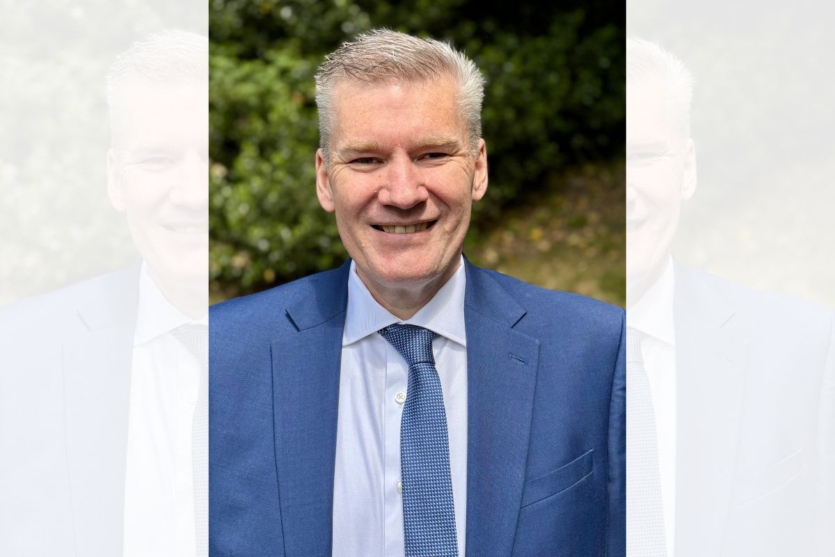 A man in a suit and tie, smiling, looking straight at the camera.